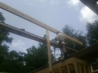 Carpenter setting a ridge beam over a new addition frame — Ice Dam Removal by Roofing Brothers in Maurice