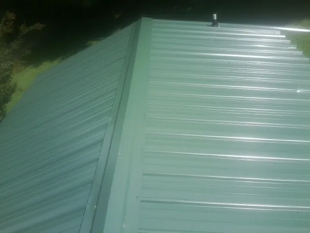 New green metal panels meeting at the ridge of a roof — Flat Roof Repair work by our crew in Maurice
