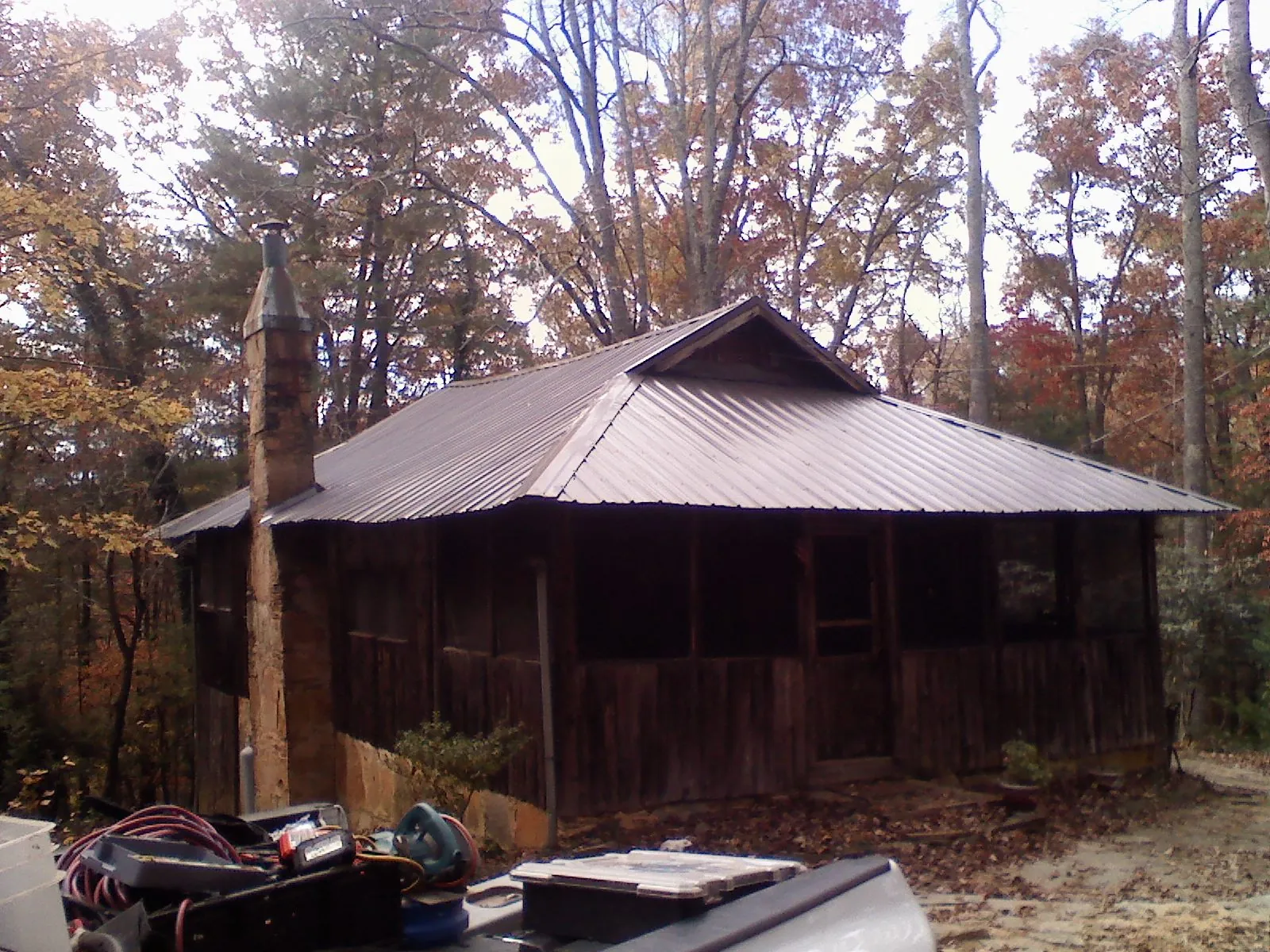 Brown metal hip roof on an old cabin with a stone chimney in Maurice