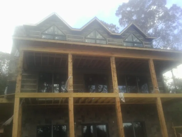 Dormers and porch framing on a large log home under construction — Roof Coating work by our crew in Maurice