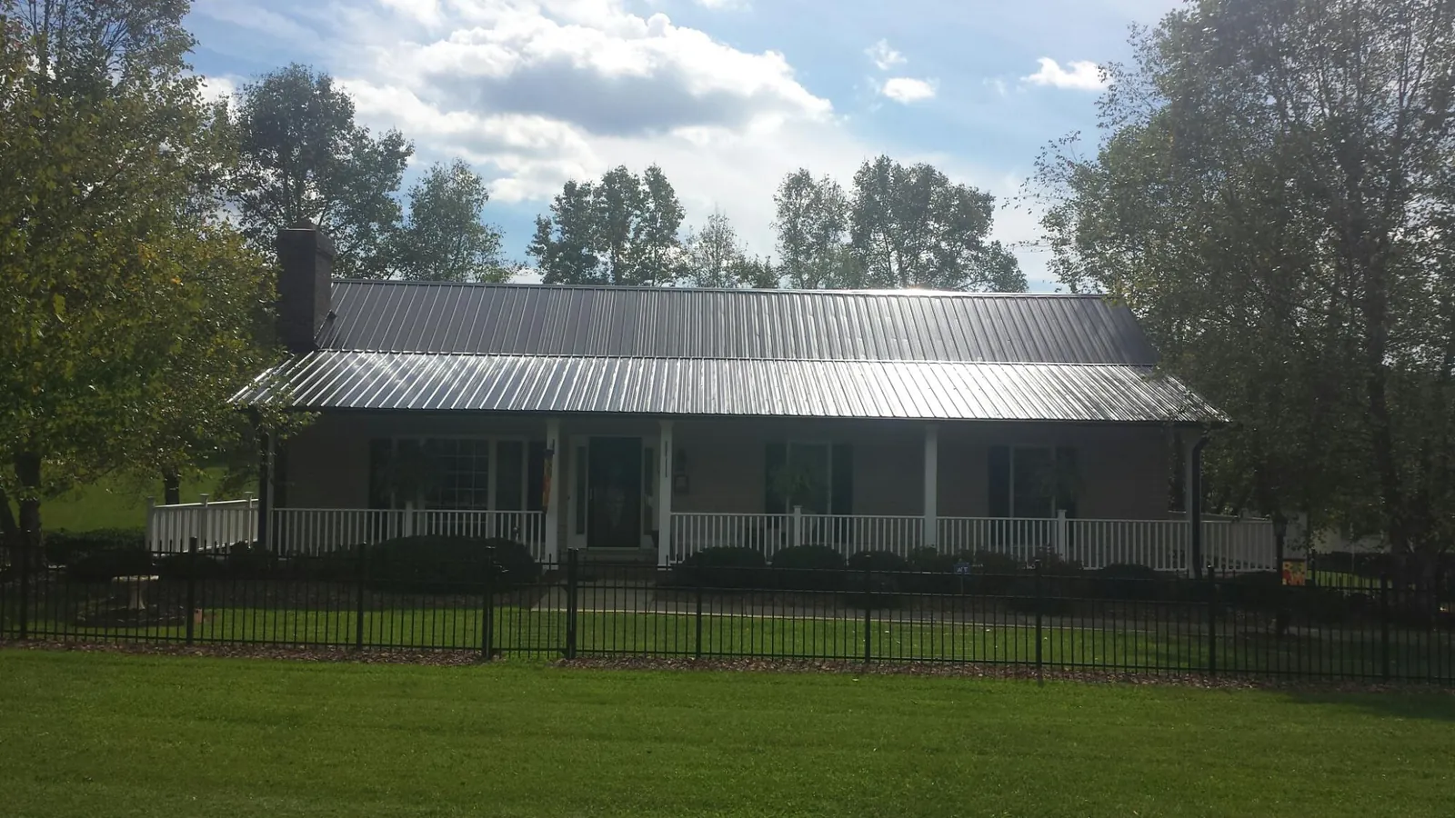 Gray metal roof on a brick ranch with a full width front porch — Gutter Guard Installation work by our crew in Maurice