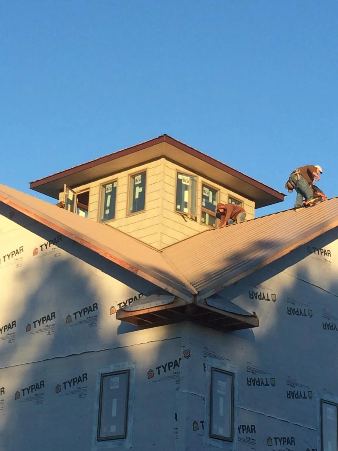 Roofers working around a rooftop cupola on a new metal roof at sunset — Roof Waterproofing in Maurice by Roofing Brothers